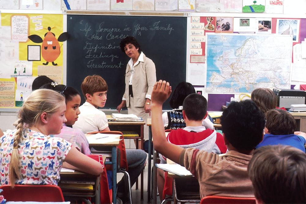 Children raising their hands to answer in a bright classroom